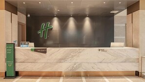 A reception desk with a modern design, a large illuminated letter, and a sign indicating the reception area. - Holiday Inn Dujiangyan Ancient Town (Chengdu)