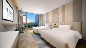 A hotel room with two beds, a desk, and a large window with a city view. - Holiday Inn Dujiangyan Ancient Town (Chengdu)