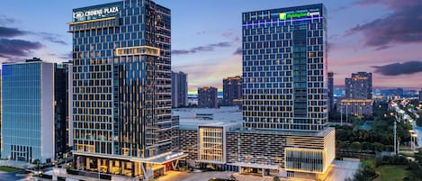 A modern hotel complex with a glass facade, multiple entry points, and a well-maintained surrounding area.