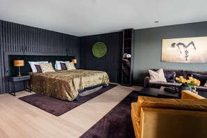 A modern bedroom with a bed, a sofa, a coffee table, and a wall-mounted shelf.