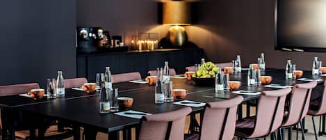 A conference room with a long table, chairs, and a television screen.
