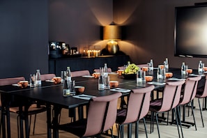 A conference room with a long table, chairs, and a television screen.