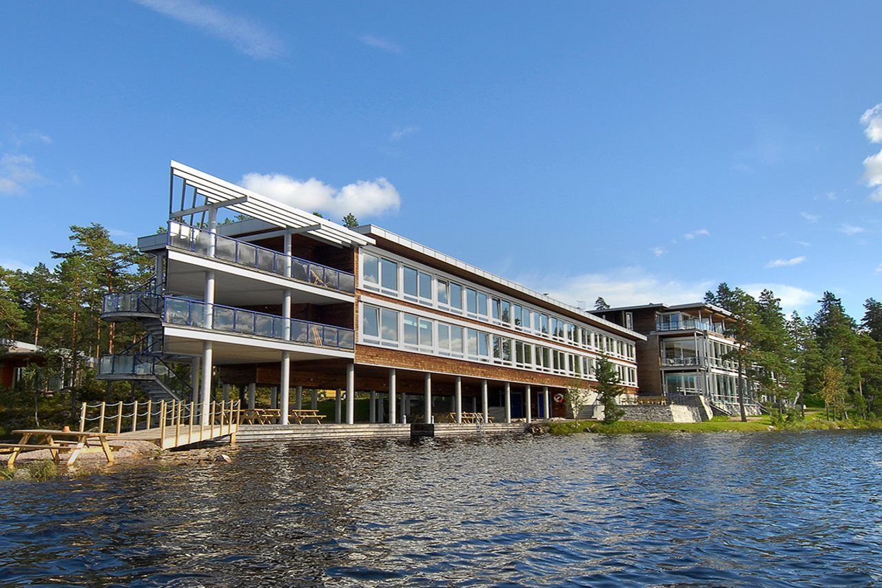 En flervåningsbyggnad vid vattnet med balkonger, en brygga och fri utsikt över vattnet.