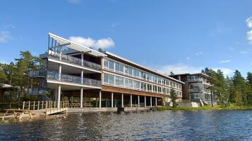 En flervåningsbyggnad vid vattnet med balkonger, en brygga och fri utsikt över vattnet.