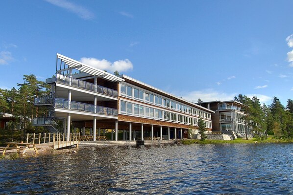 A multi-story waterfront building with balconies, a dock, and a clear view of the water. - Rømskog Hotel Spa & Resort (Rømskog)