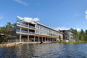 A multi-story waterfront building with balconies, a dock, and a clear view of the water.
