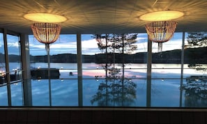 A room with large windows, a ceiling with a grid pattern, and two hanging light fixtures.