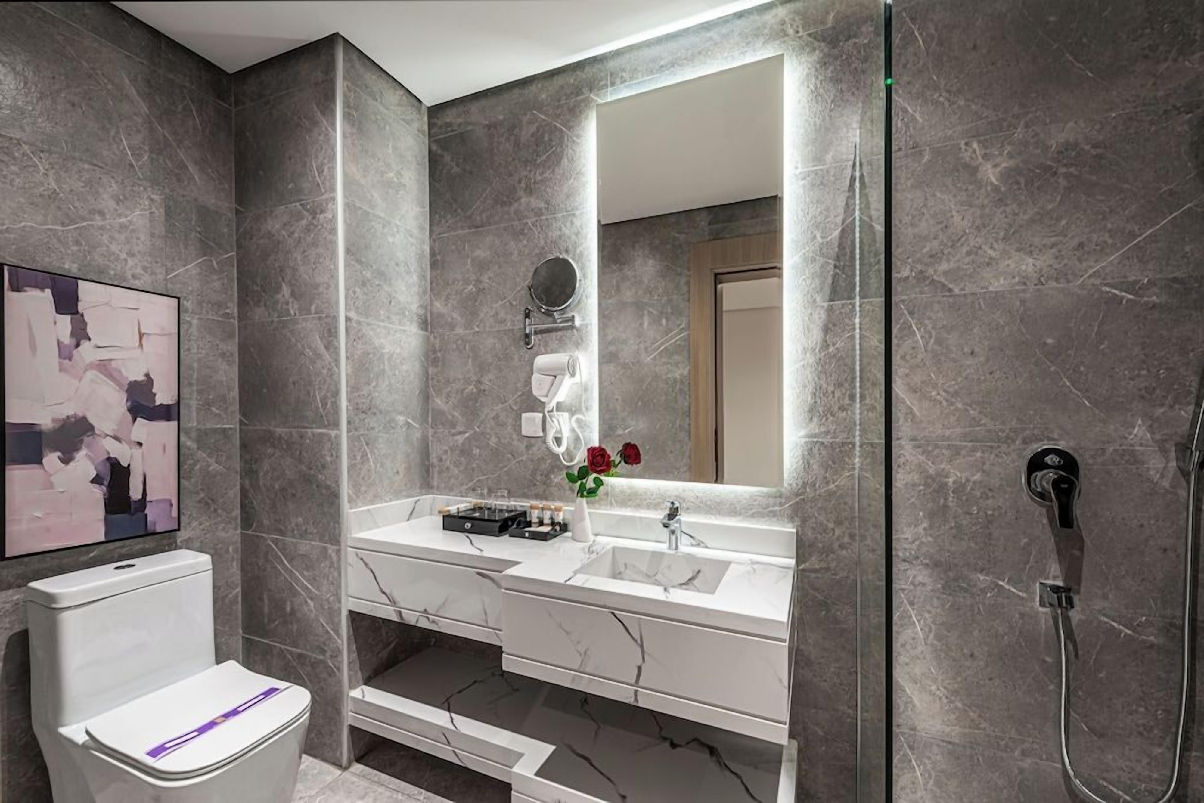 Un baño moderno con lavabo de mármol, inodoro y ducha.
