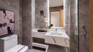 Une salle de bain moderne avec un lavabo en marbre, une douchette à main et un grand miroir.