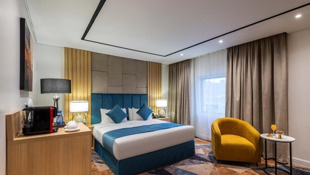 Une chambre d’hôtel avec un lit, un bureau, une chaise et une petite table avec une boisson.