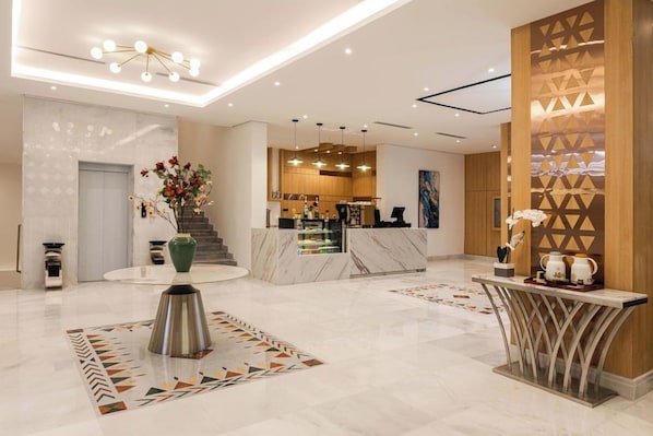 Un moderno vestíbulo de hotel con una recepción, una escalera y una pared decorativa.