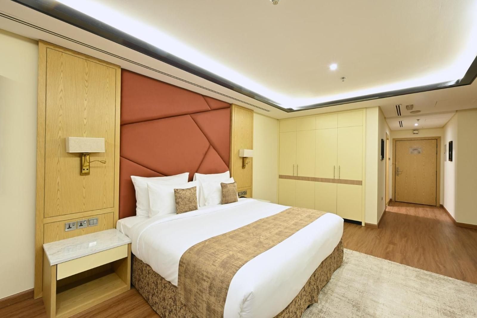 A hotel room with a large bed, wooden wardrobe, and a walk-in closet.