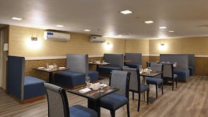 A hotel dining area with booths and tables, air conditioning units, and patterned wall designs. - Pavilion Palace Hotel (Sharjah)