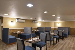 En hotellrestaurang med avskilda sittplatser, bord, luftkonditionering och väggar med ett dekorativt mönster.