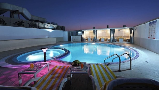 A rooftop swimming pool with lounge chairs and a hot tub, surrounded by walls with decorative patterns. - Pavilion Palace Hotel (Sharjah)