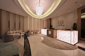 En modern hotellobby med en receptionsdisk, soffor och en kristallkrona.
