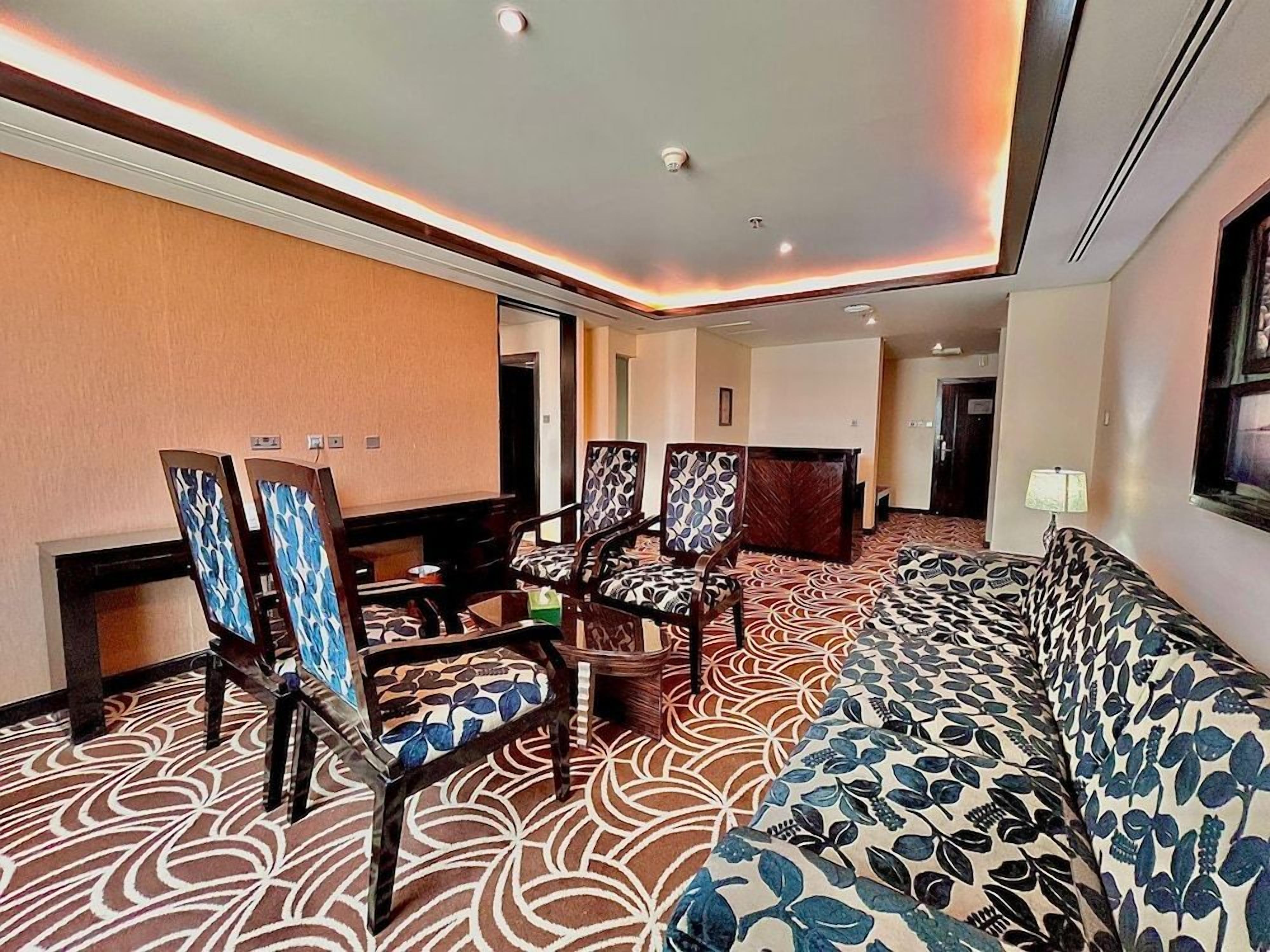 Ein Hotelzimmer mit einem gemusterten Teppich, einem Sofa und zwei Stühlen mit gepunkteter Polsterung.