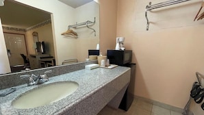 A bathroom with a granite countertop sink, a mirror, a towel rack, and a shower area. - Seminole Inn Near New Mexico Hwy 62 (Seminole)