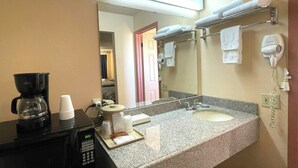 A hotel bathroom with a coffee maker, a sink, a mirror, and a hairdryer. - Seminole Inn Near New Mexico Hwy 62 (Seminole)