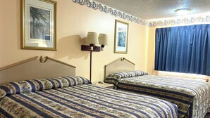 A hotel room with two beds, a nightstand, a lamp, and a window with curtains. - Seminole Inn Near New Mexico Hwy 62 (Seminole)