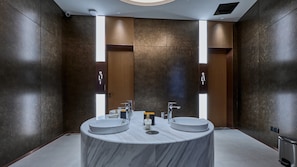 Un baño moderno con dos lavamanos, un tocador de mármol y un inodoro de pared.