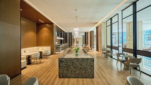 A modern hotel lobby with a central marble reception desk, seating areas, and large windows offering views of the city. - VM Hotel (Phnom Penh)