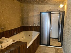 Une salle de bain dotée d’une grande baignoire, d’un espace douche et d’un meuble-lavabo en bois.