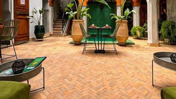 Een binnenplaats met een centraal zitgedeelte, omringd door witte muren met houten balkons en potplanten.