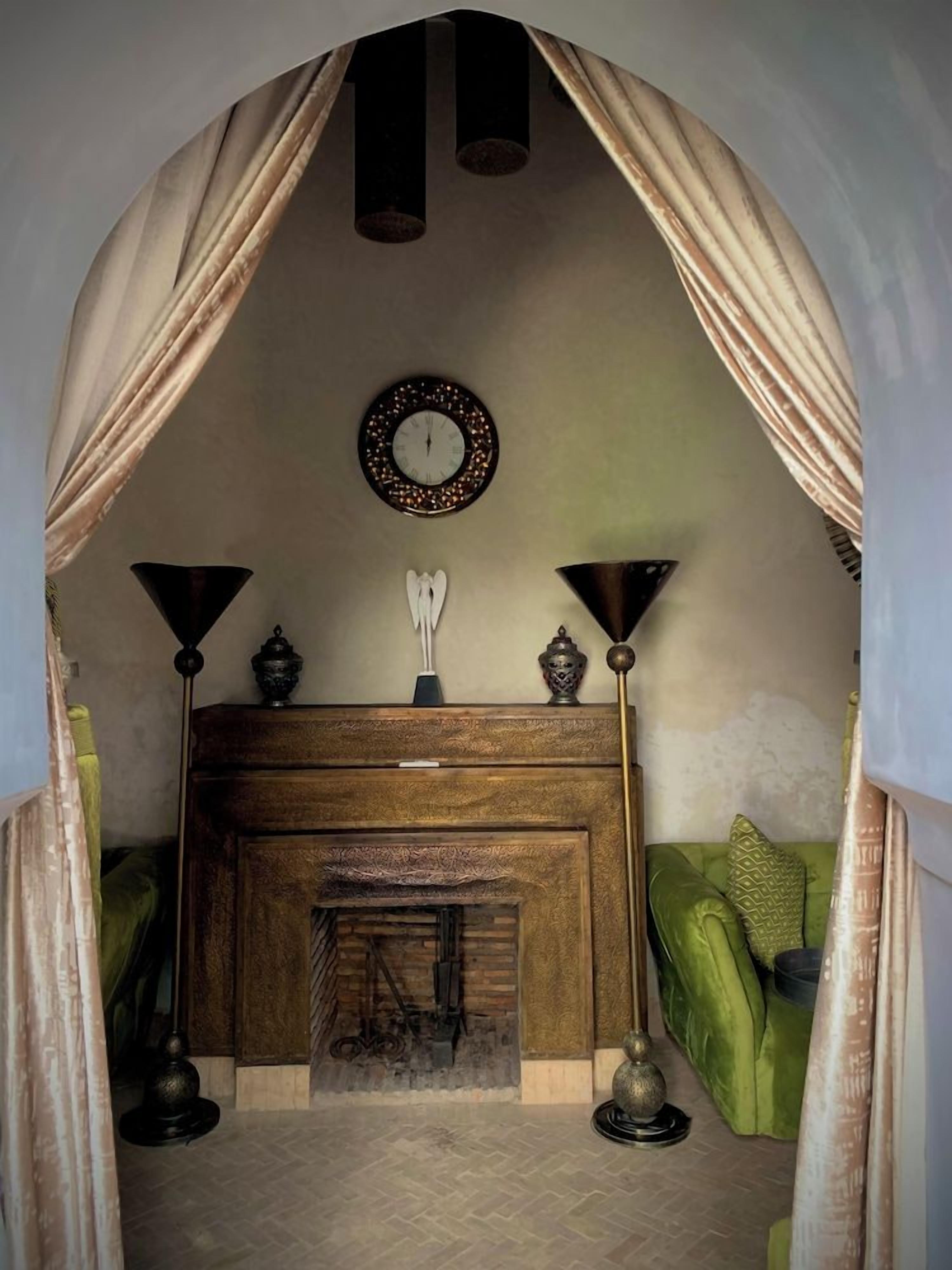 A room with a fireplace, a clock on the wall, and a green sofa.