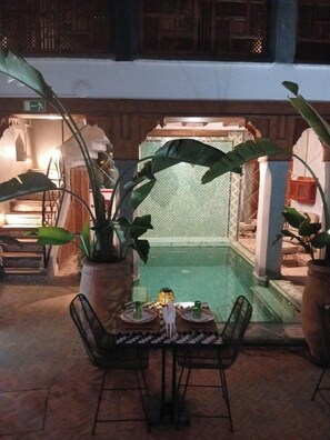 An outdoor pool area with a seating arrangement and potted plants. - Riad BAB Yacout Piscine and SPA (Marrakech)