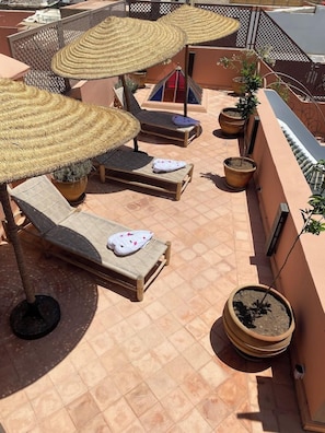 A rooftop terrace with lounge chairs, woven umbrellas, and potted plants. - Riad BAB Yacout Piscine and SPA (Marrakech)