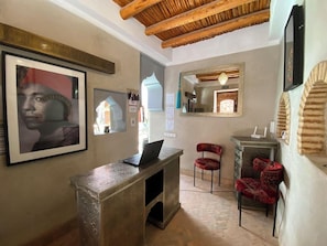 A reception area with a desk, chairs, framed artwork, and a mirror. - Riad BAB Yacout Piscine & SPA (Marrakech)