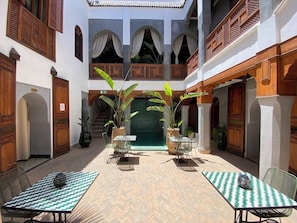 A courtyard with a central water feature, surrounded by wooden balconies and potted plants. - Riad BAB Yacout Piscine & SPA (Marrakech)