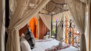 Een bed met hemelbed, een kroonluchter en uitzicht op een buitengebied.