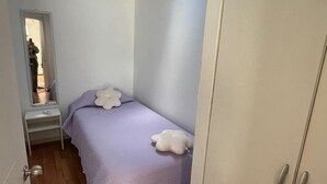 A bedroom with a bed, a wardrobe, a small table, and a skylight. - Departamentos Egaña (Puerto Montt)