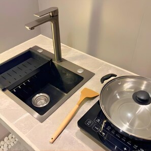 Cozinha com pia, fogão e espátula.