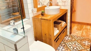 Een badkamer met een houten wastafelmeubel, een witte wasbak en een spiegel.