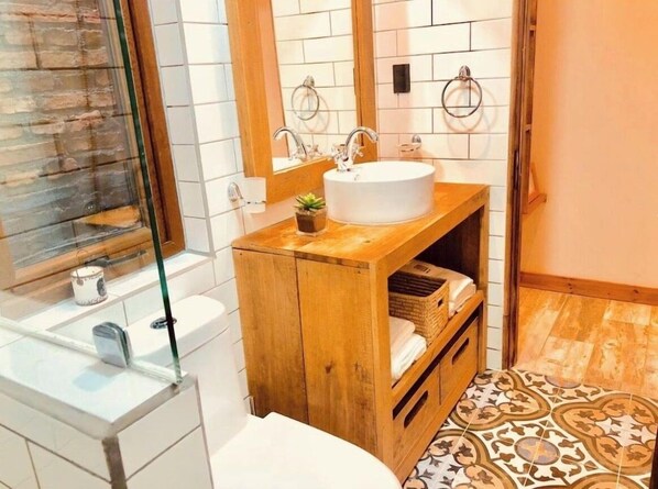 Een badkamer met een houten wastafelmeubel, een witte wasbak en een vloer met een patroon.