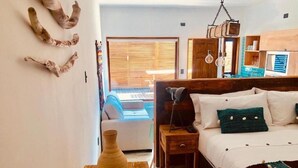Een slaapkamer met een bed, nachtkastje en een houten bijzettafeltje.