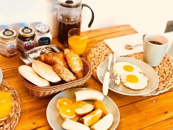A breakfast setting with bread, eggs, and juice on a wooden table. - DT Loft (Natales)