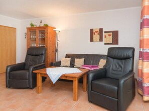 A living room with a sofa, two armchairs, a wooden cabinet, and a table with a lamp. - 1.3/t2 Holiday Home Park \"freesenbruch\" (Zingst)