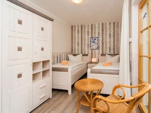 A small, compact room with two single beds, a small table, and a wicker chair. - 1.3/t2 Holiday Home Park \"freesenbruch\" (Zingst)