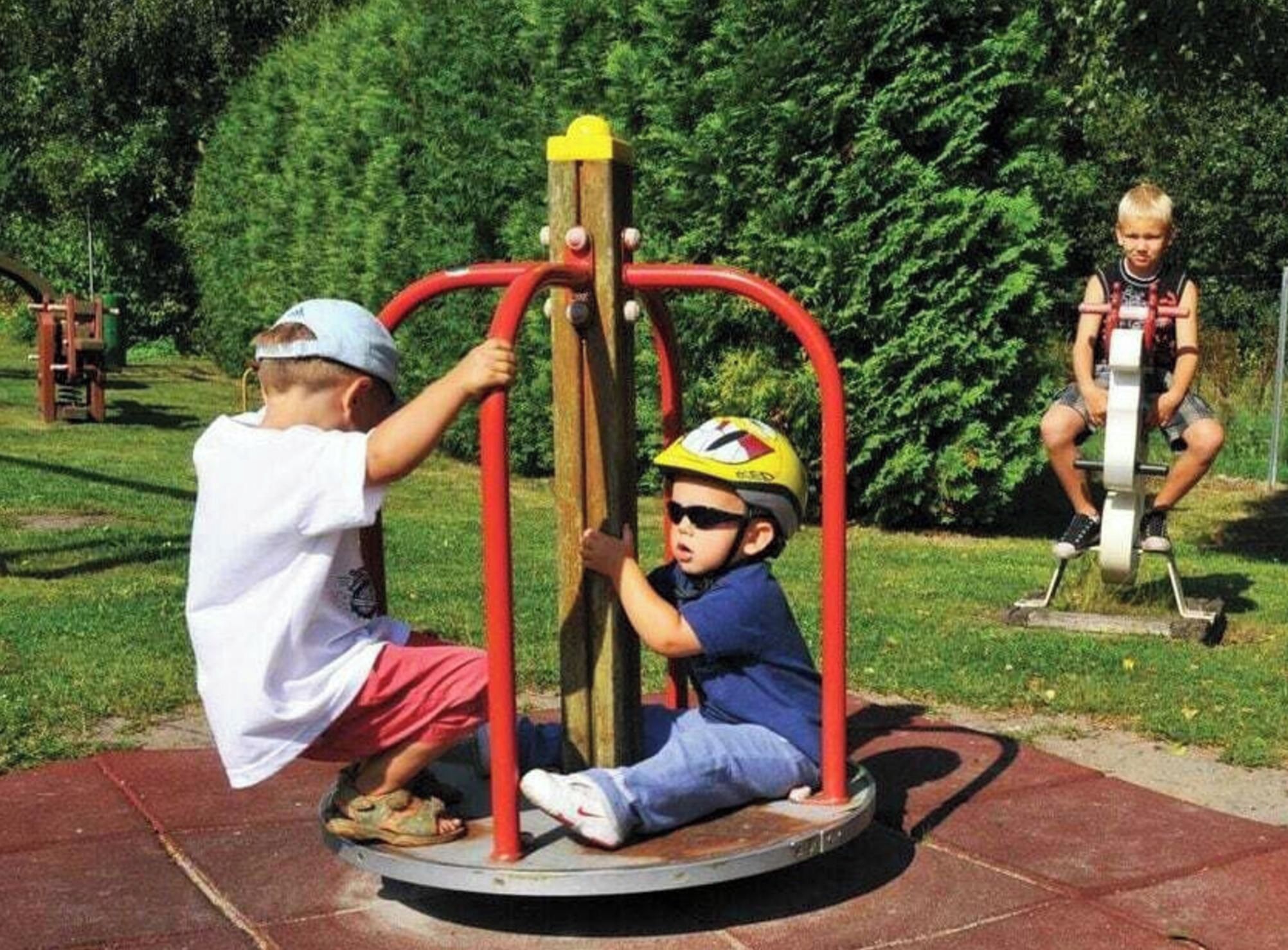A playground with a rotating swing set and a stationary swing.