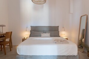 Un dormitorio ordenado con cama, mesitas de noche, un escritorio y un espejo.