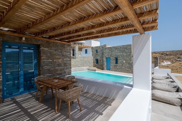 Ein Poolbereich mit einer Holz-Pergola, Steinmauern und Blick auf die Landschaft.