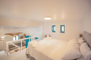 A bedroom with a bed, a staircase, a window, and a wall-mounted light fixture. - Anemela Mykonos Villas & Suites (Mykonos)