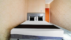 Een hotelkamer met een groot bed, een hoofdbord en behang met een patroon.