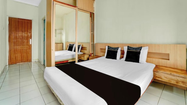Een hotelkamer met een groot bed, een houten hoofdeinde, een kledingkast en een spiegel.