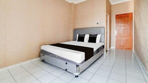 Een hotelkamer met een bed, een deur en een betegelde vloer.