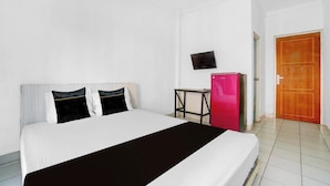 Een hotelkamer met een bed, een aan de muur bevestigde televisie, een klein tafeltje en een deur.